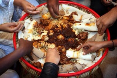 A family sharing a platter of doro wat during the Fasika celebration.
